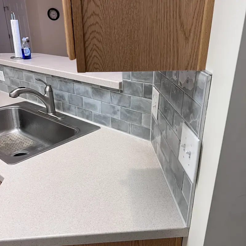 Kitchen sink with gray subway tile backsplash mid-install
