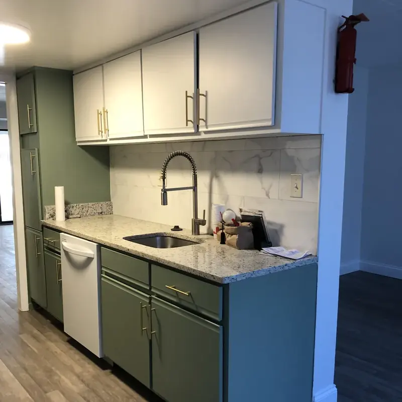 Green cabinet kitchen with granite counters and dishwasher