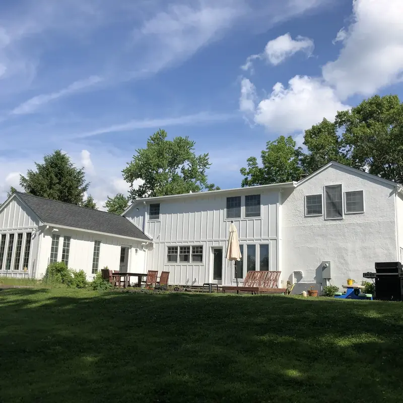 Backyard view of two-story home with deck and grill