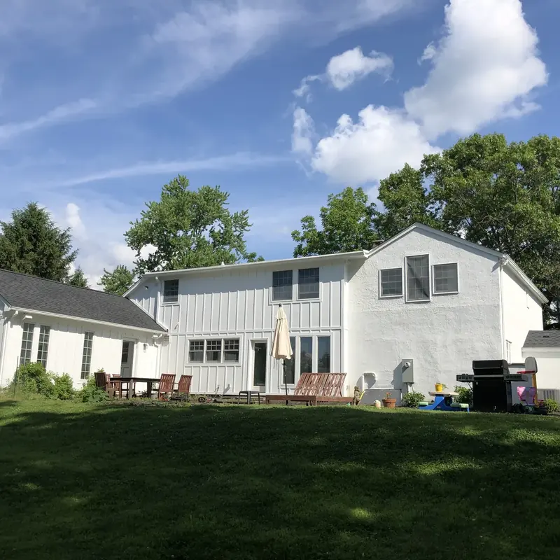 Backyard view of two-story home with patio furniture
