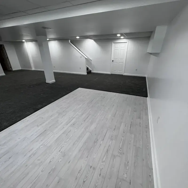 Finished basement with light wood floor and stairs