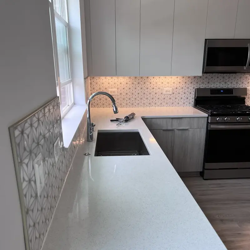 Kitchen with white quartz counters, sink, gas range