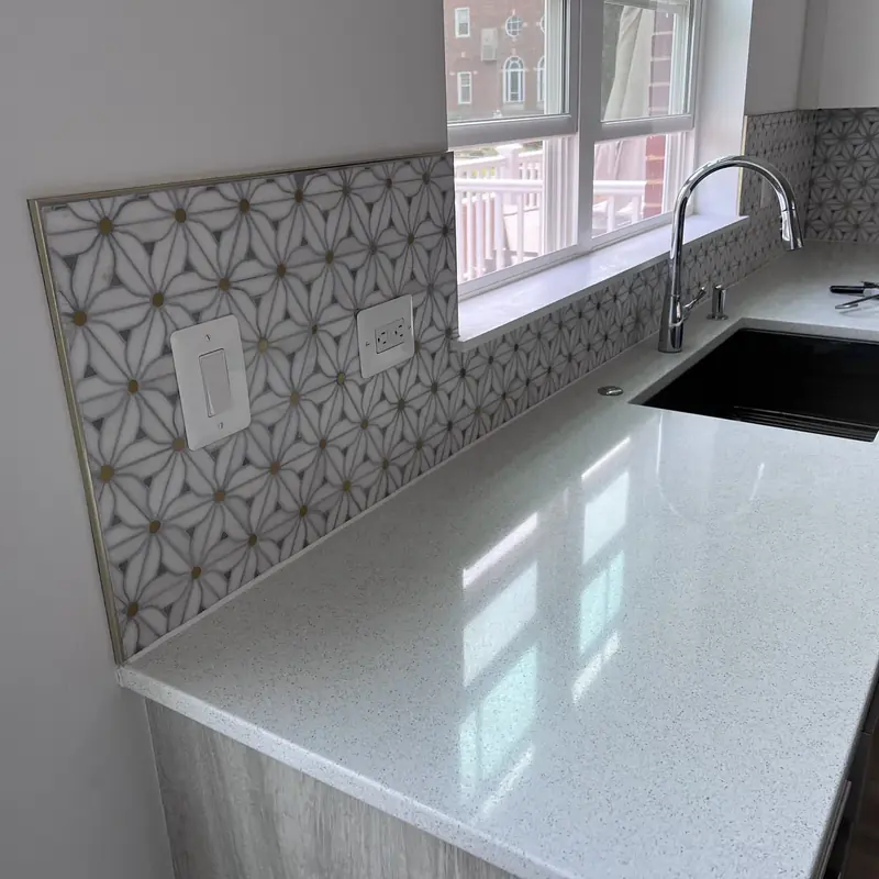 white quartz countertop with geometric tile backsplash and sink