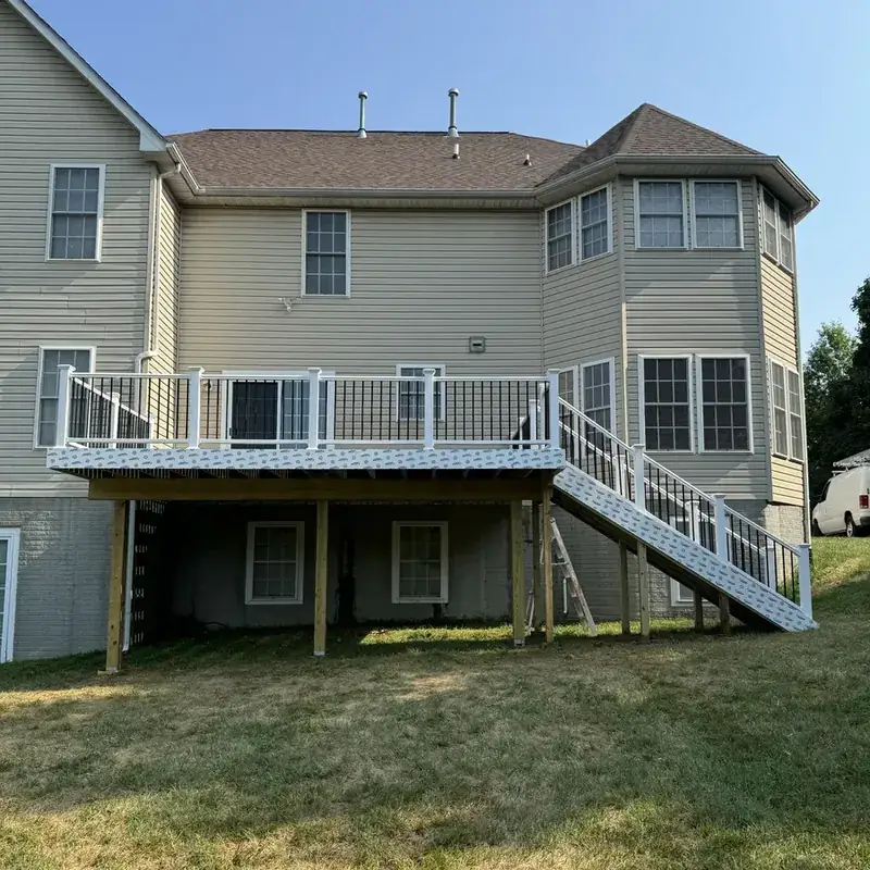 Elevated white-railing deck on tan vinyl-sided house