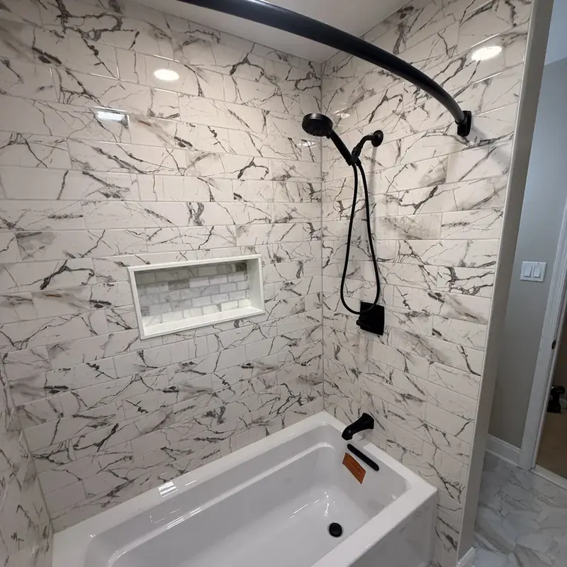 Marble-tiled shower tub with niche and black fixtures