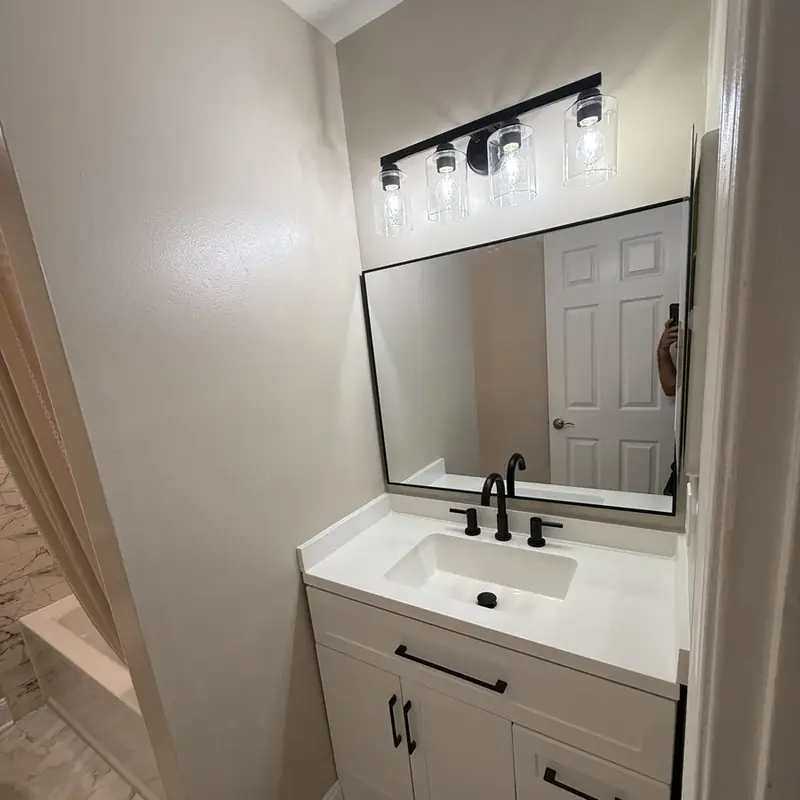 White vanity with black faucet and large mirror