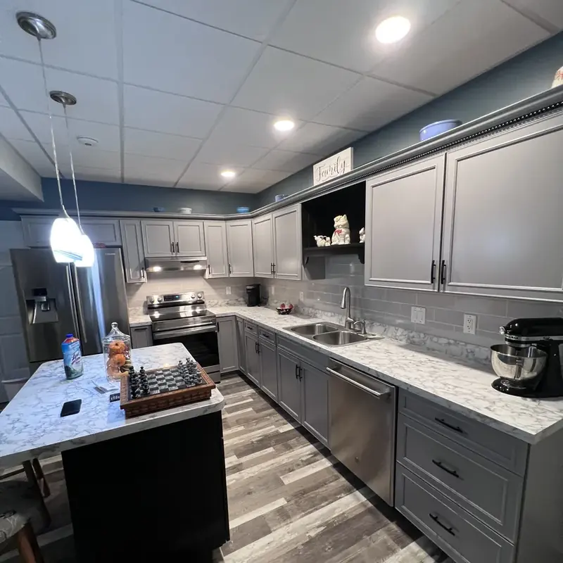 Basement kitchen with gray cabinets, island, stainless appliances