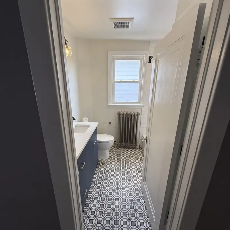 Bathroom with patterned tile floor, blue vanity, radiator