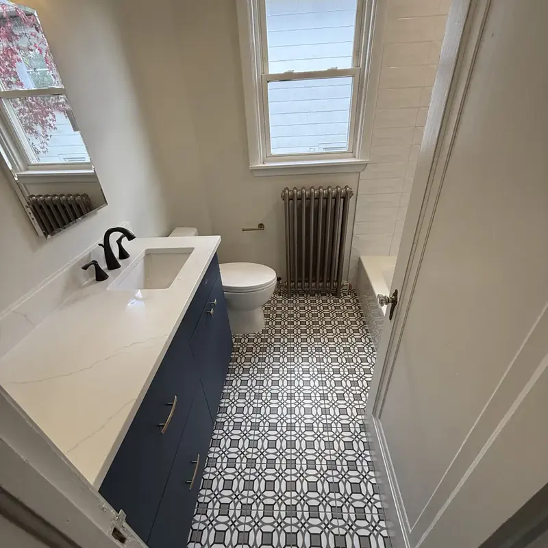 Bathroom with patterned tile floor, blue vanity, radiator