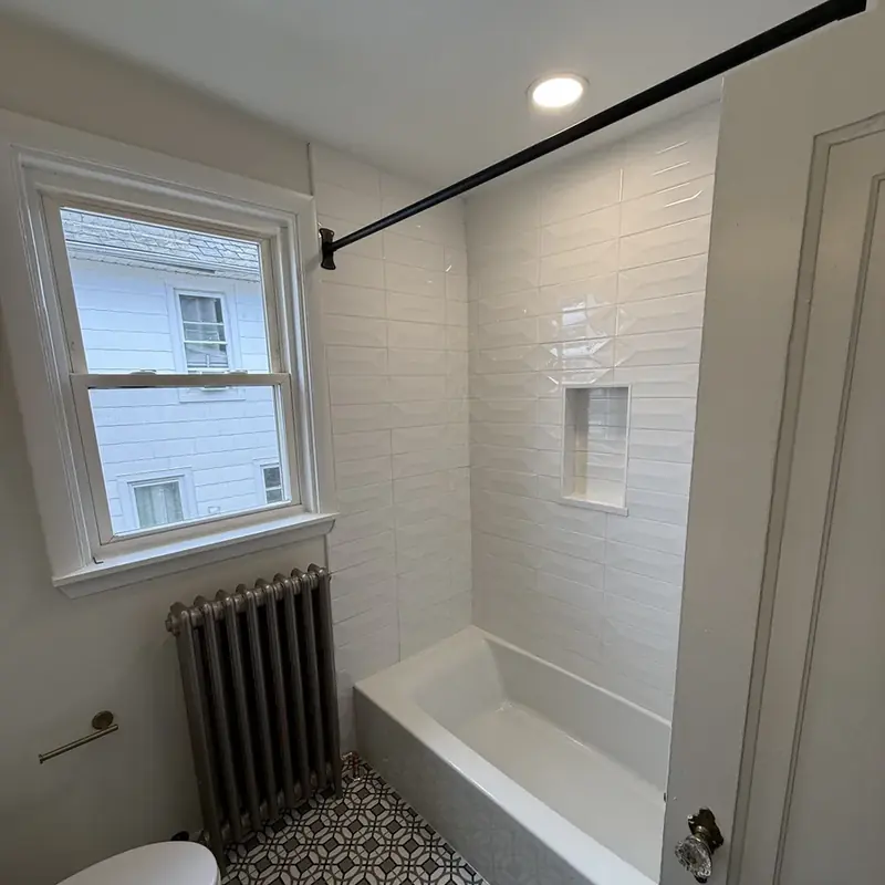 white tile tub surround with window and radiator