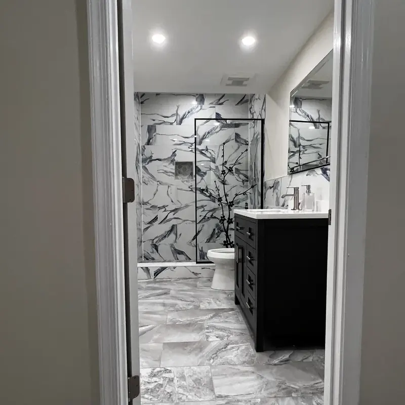 marble-look bathroom with black vanity and walk-in shower