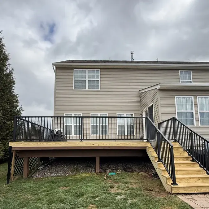New wood deck with black metal railings on home