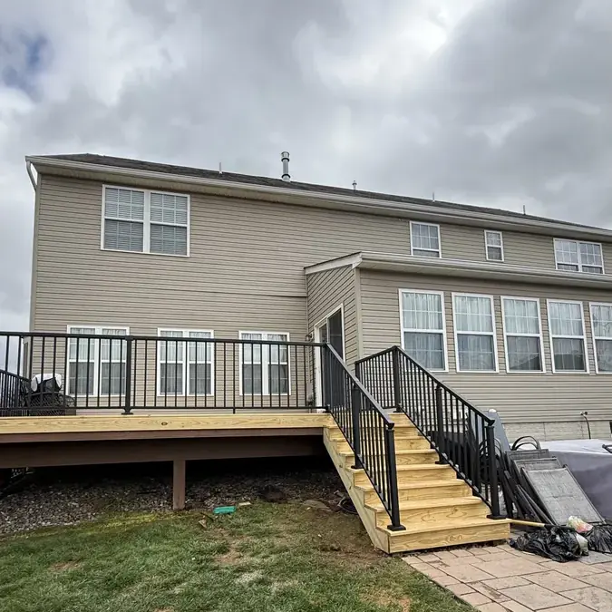 Wood deck with stairs and black railings rear of house
