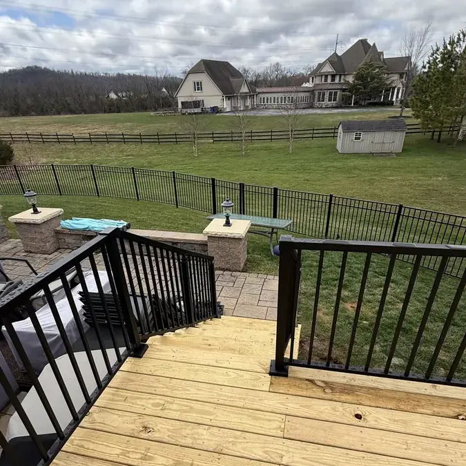 Deck stairs leading down to paver patio backyard