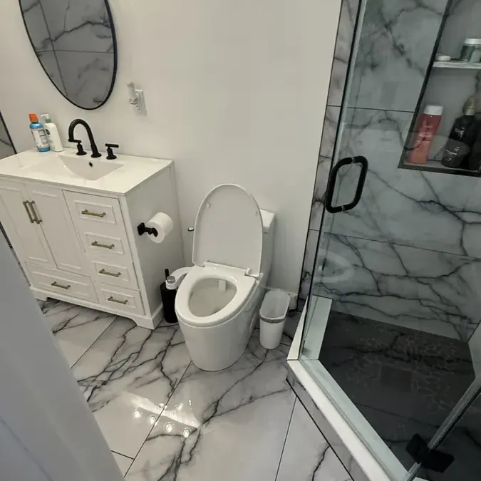 Bathroom with white vanity toilet and marble shower