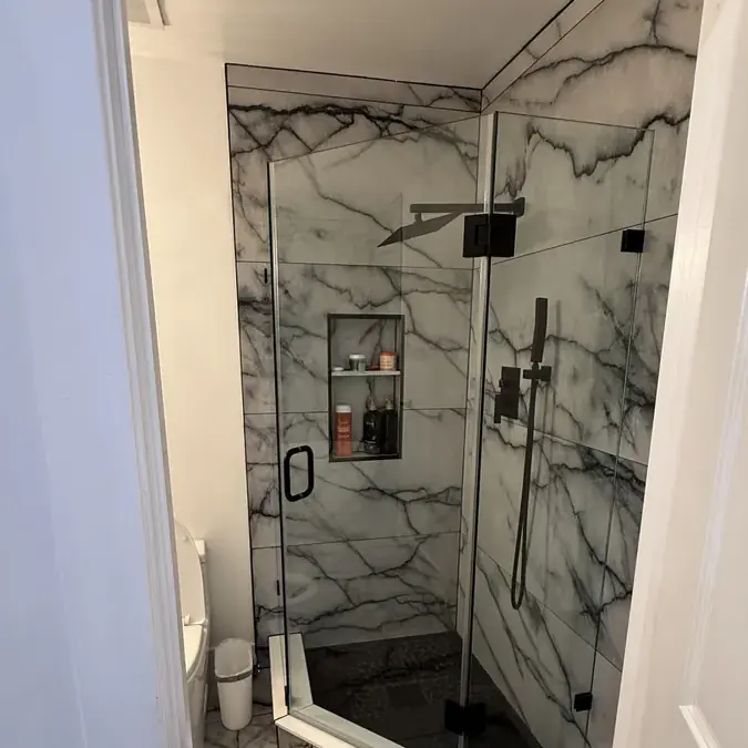 Glass marble walk-in shower with black fixtures and niche