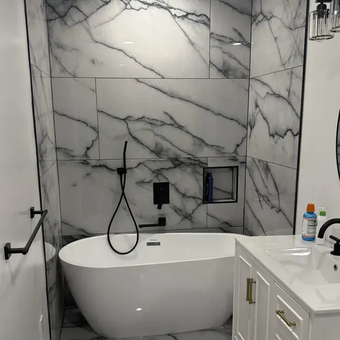 Freestanding white tub with marble walls and black fixtures