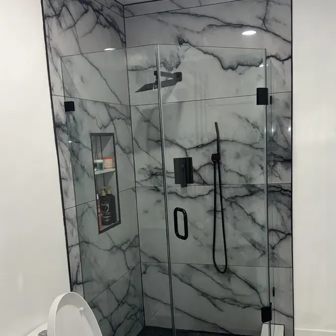 Marble walk-in shower with glass doors and black fixtures