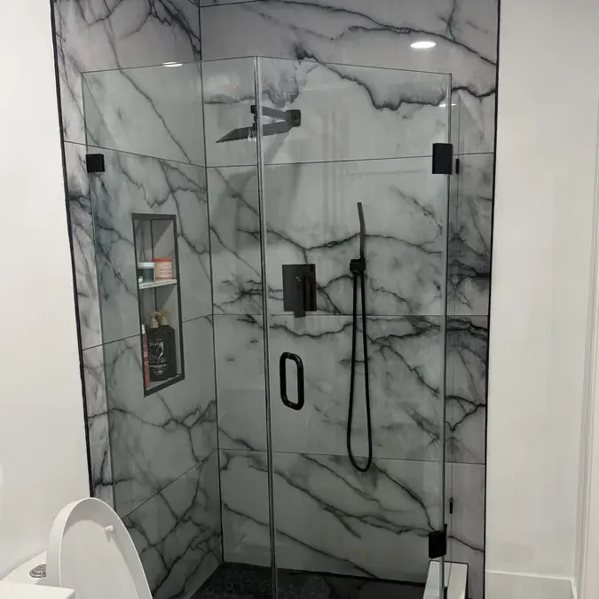 Glass marble shower with black hardware and niche