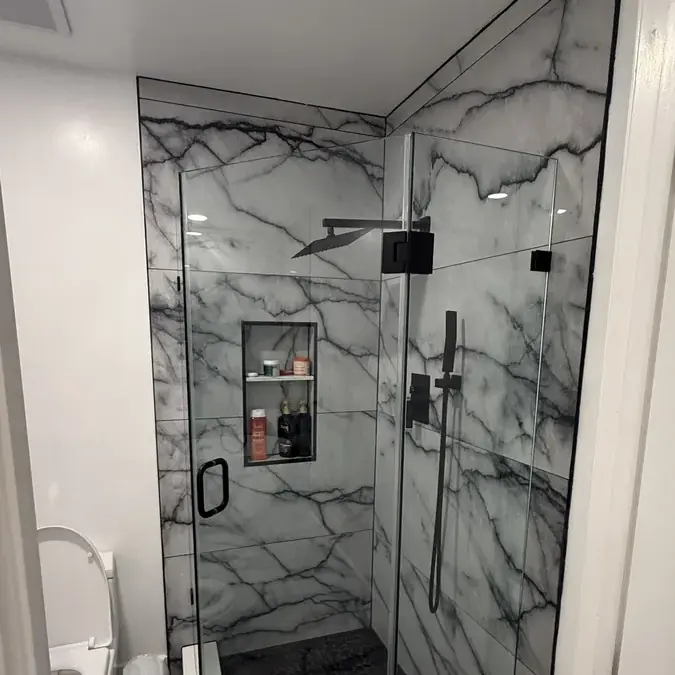 Walk-in marble shower glass enclosure with black fixtures