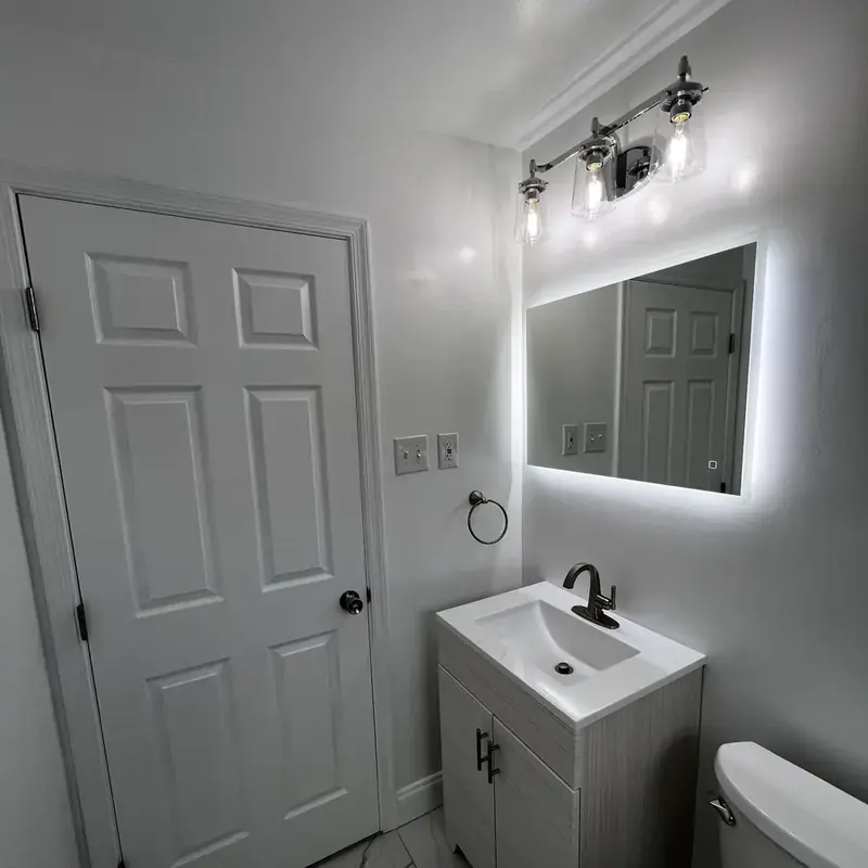 Bathroom vanity with LED mirror beside white door
