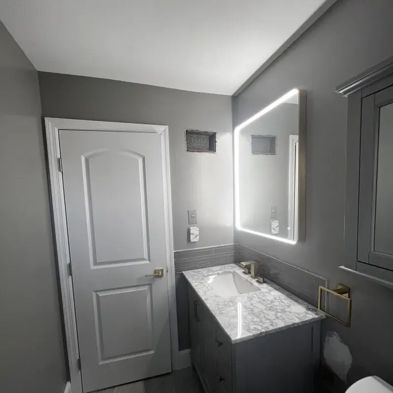 Gray vanity with LED mirror beside white door