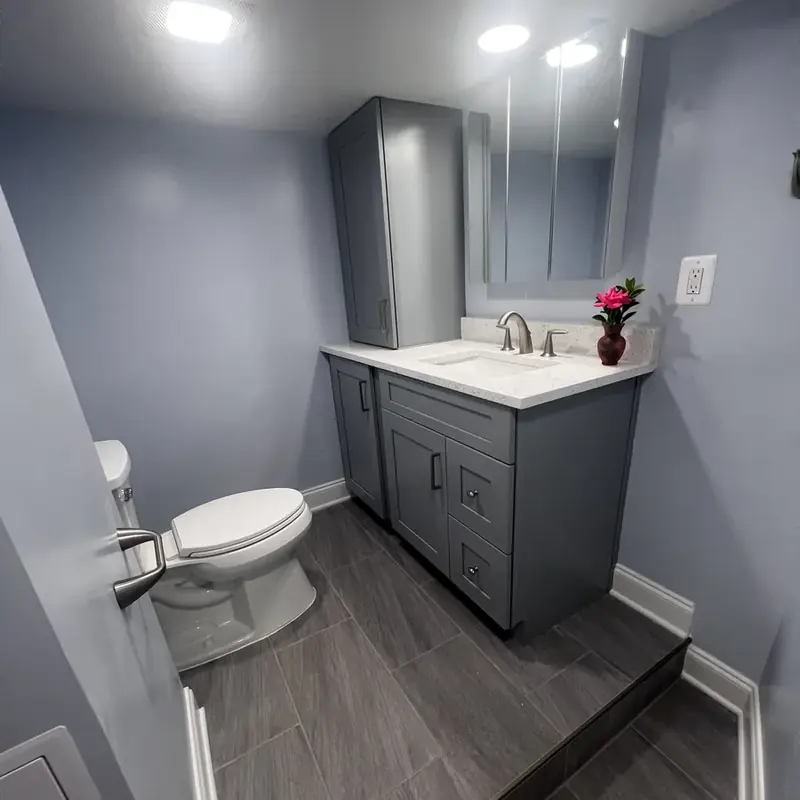 Gray vanity beside toilet with mirror and flowers
