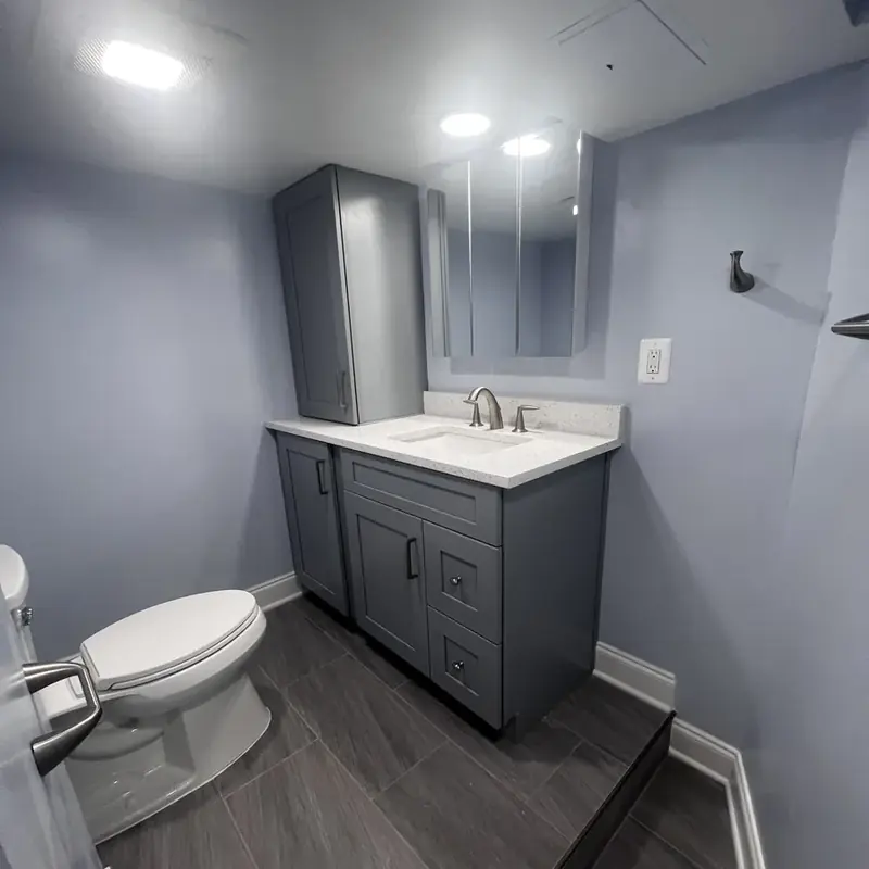 Gray vanity tall cabinet toilet on tile floor