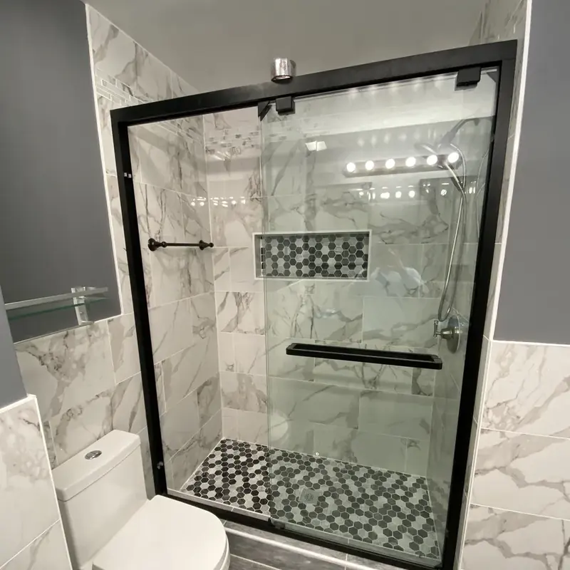 Glass walk-in shower with marble walls and mosaic floor