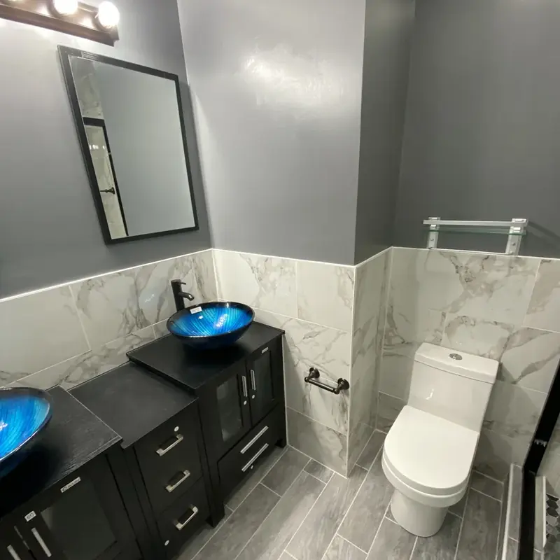 Bathroom with black vanity, blue sink, and toilet