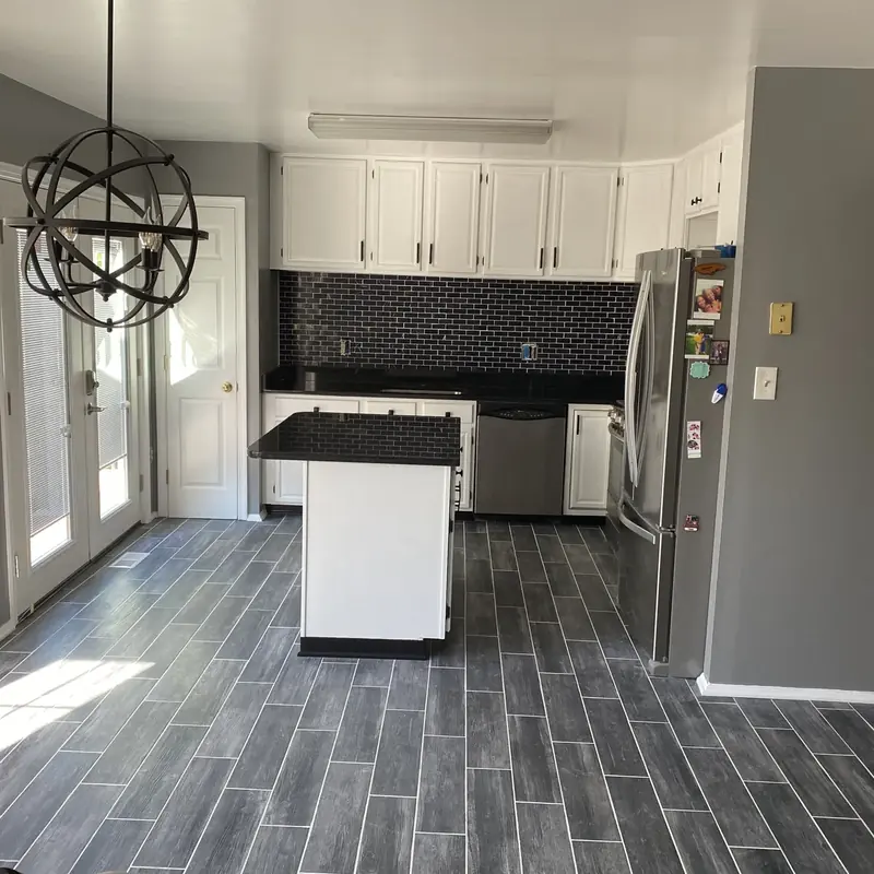 Kitchen with white cabinets, island, and dark backsplash