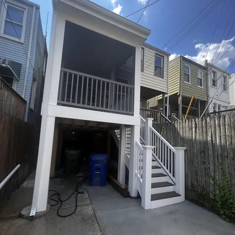Backyard raised deck with white railing and stairs