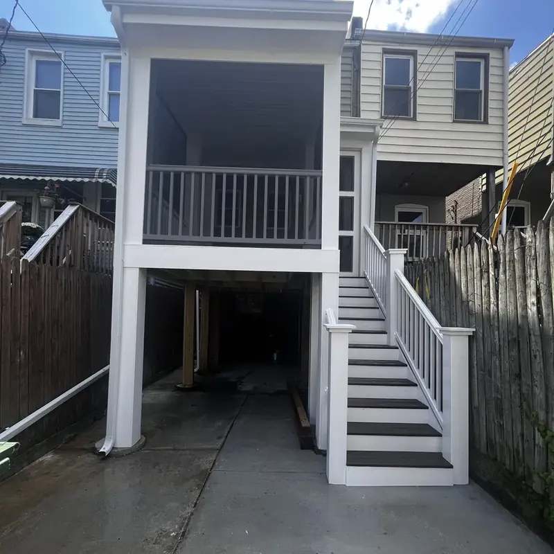 Raised deck and white stairs in narrow backyard