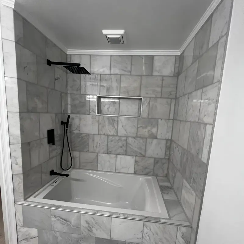 Tub and shower combo with marble tile and black fixtures
