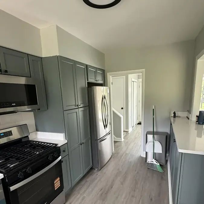 Remodeled galley kitchen with sage green cabinets and stainless gas range
