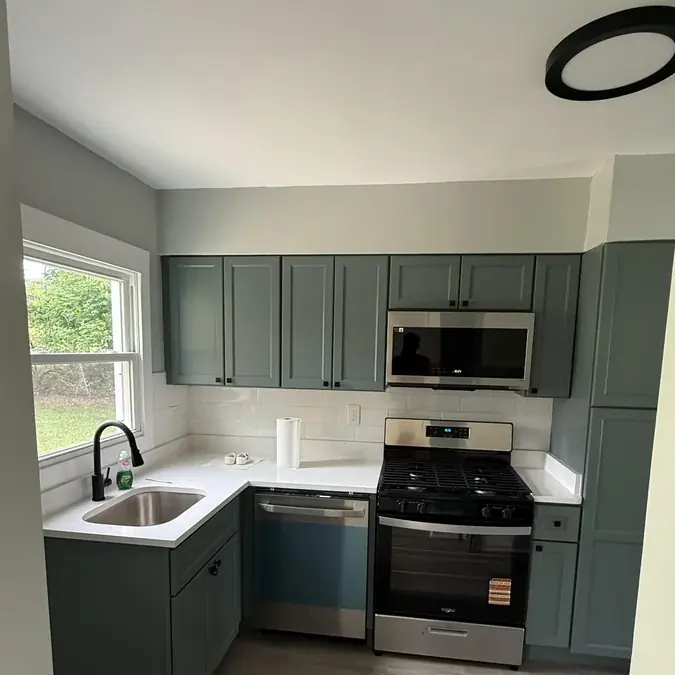 Sage green kitchen remodel with white quartz counters and subway tile backsplash